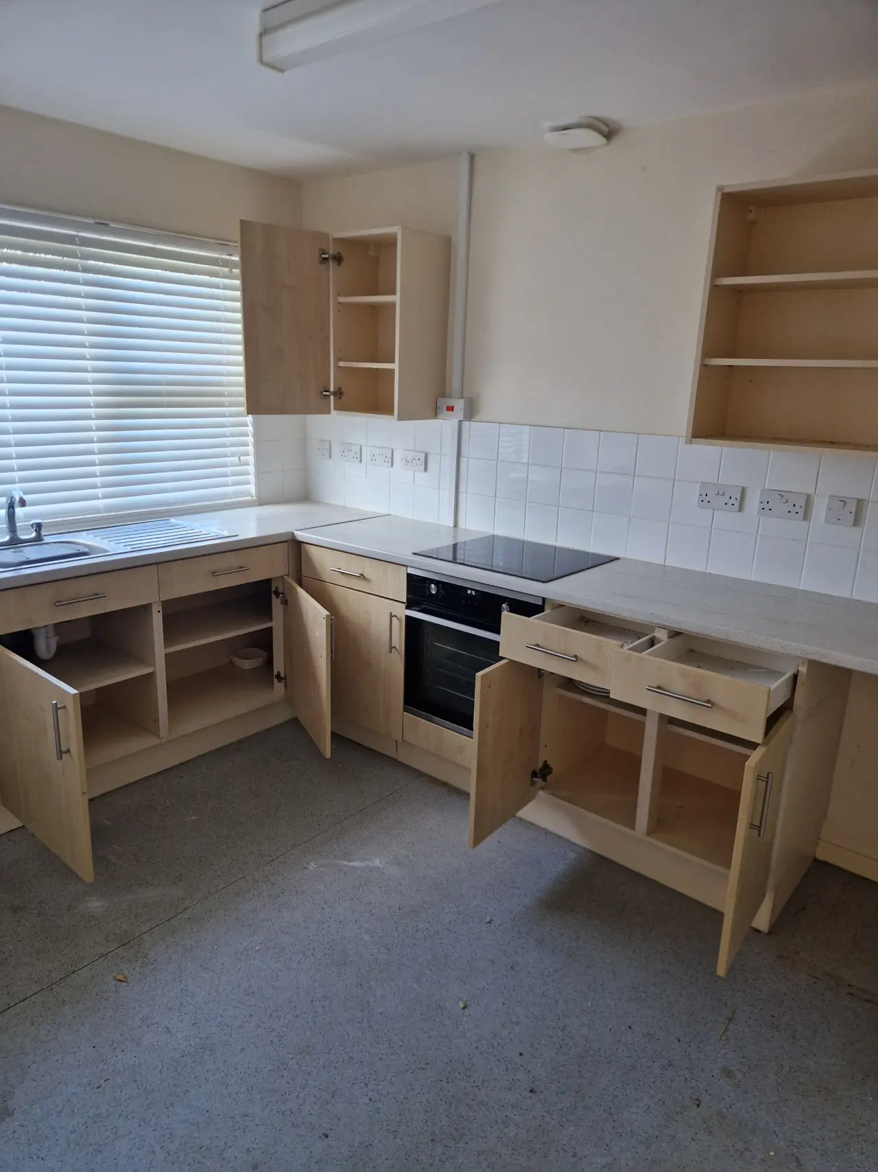Kitchen after clearance — cupboards emptied