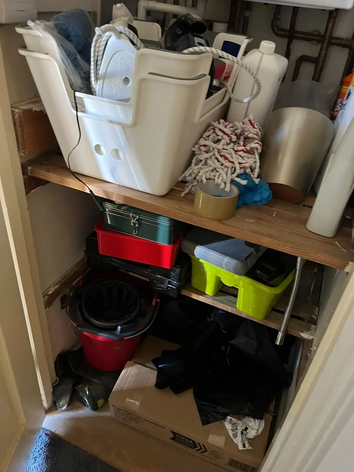 Utility cupboard full of household items before clearance